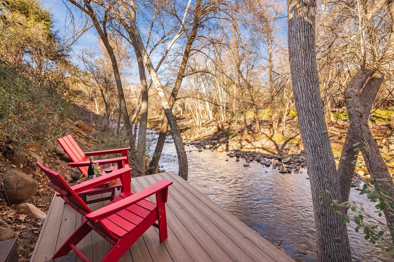 Red Adirondack chairs on creek deck facing Oak Creek
