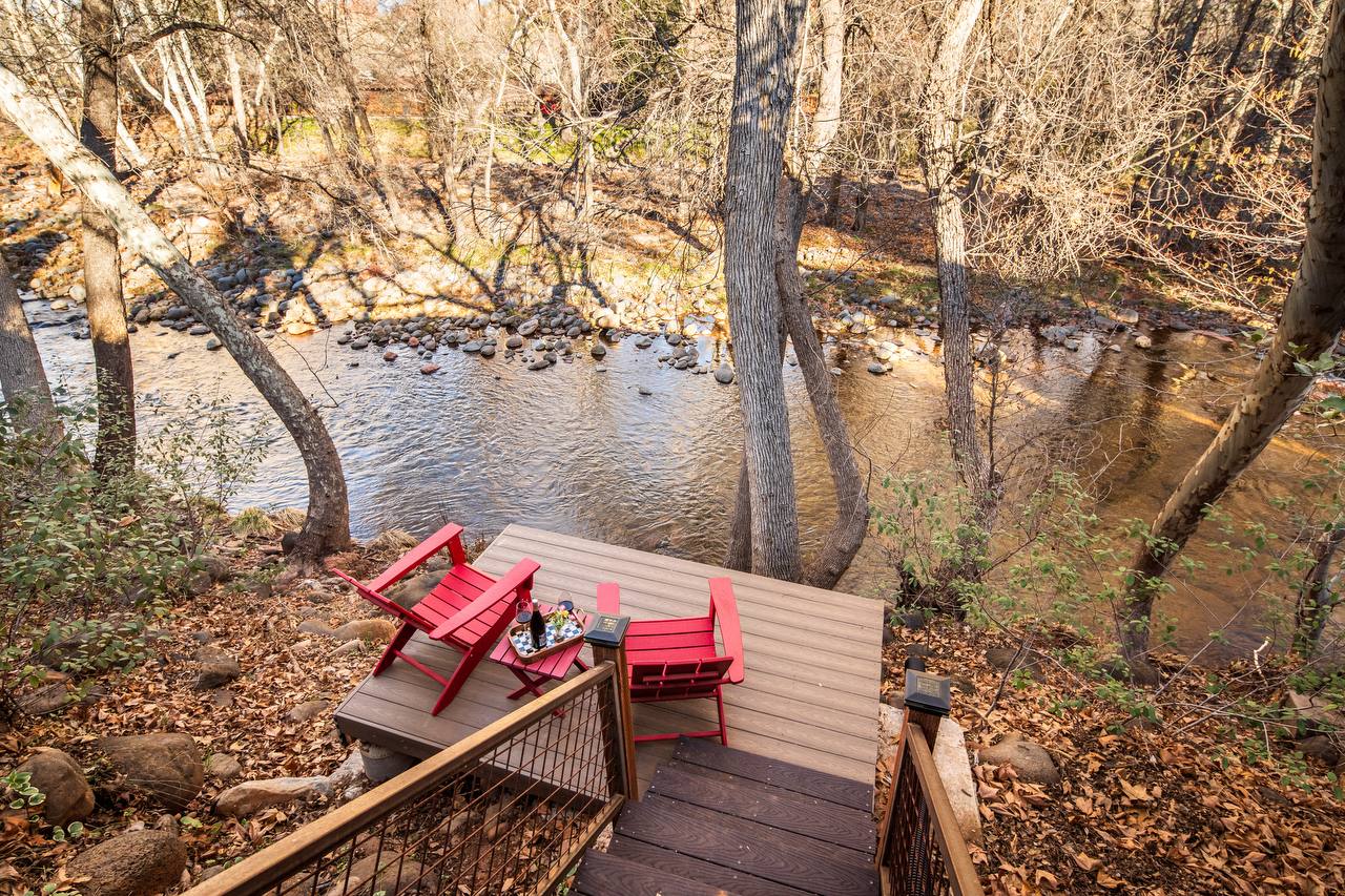 Creek deck from above with red chairs, wine, and Oak Creek