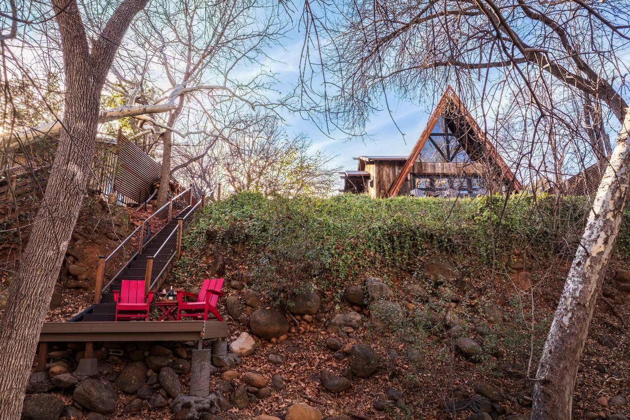 Back of Creekside 88 A-frame with stairs down to private creek deck with red chairs