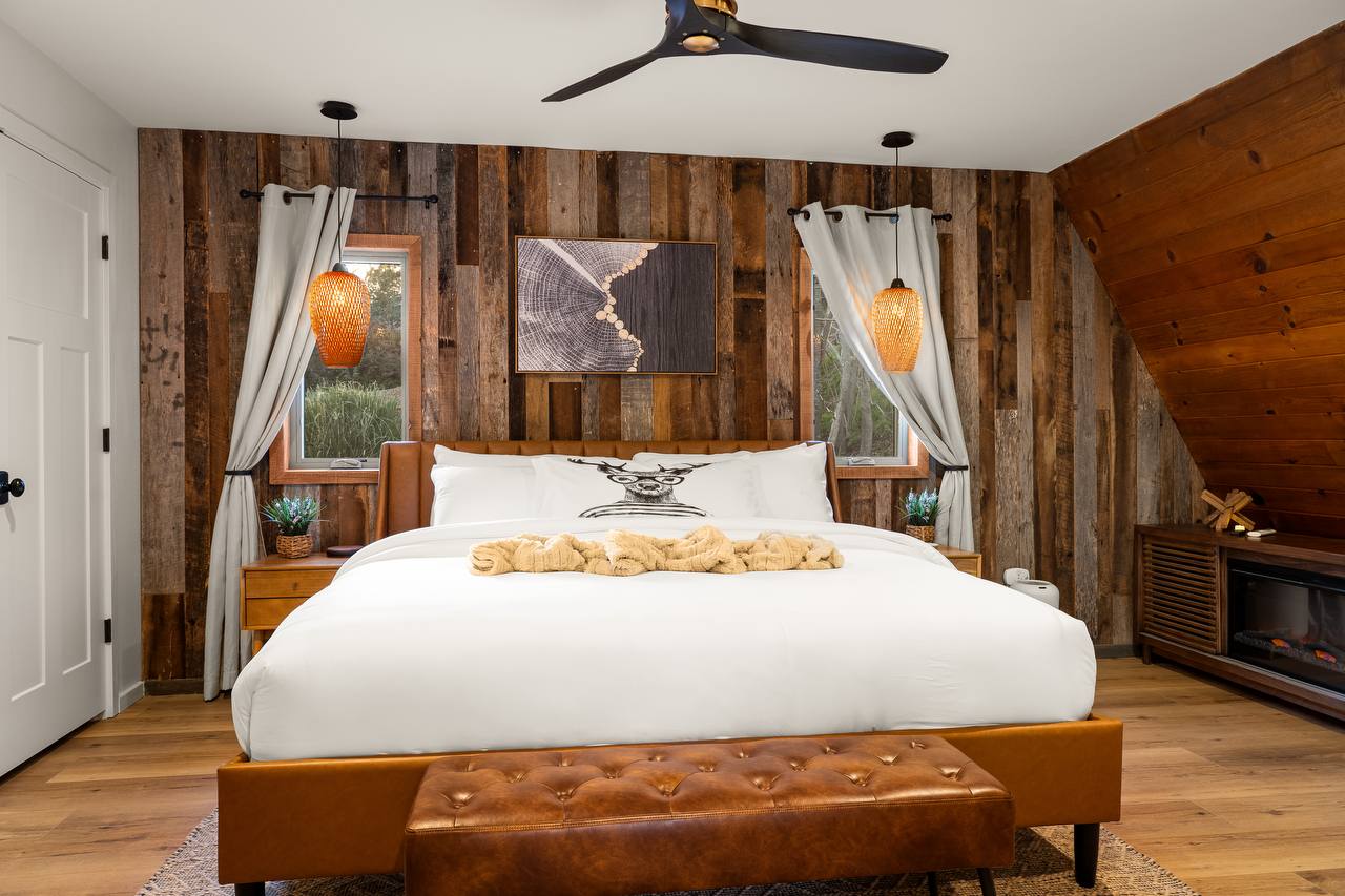 Primary bedroom with leather headboard, electric fireplace, and pendant lights
