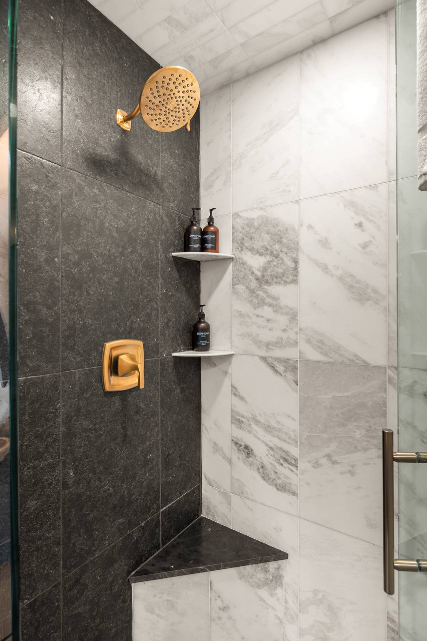 Marble shower with gold rain showerhead and premium amenities