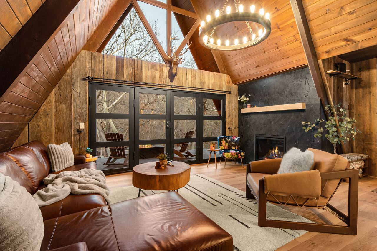 Living room with leather sectional, iron chandelier, and vaulted wood ceilings
