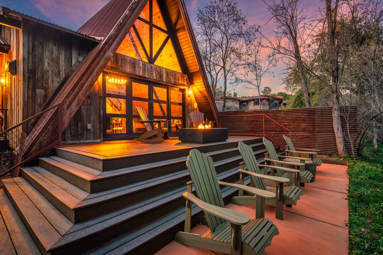 A-frame with deck, fire feature, and Adirondack chairs at sunset