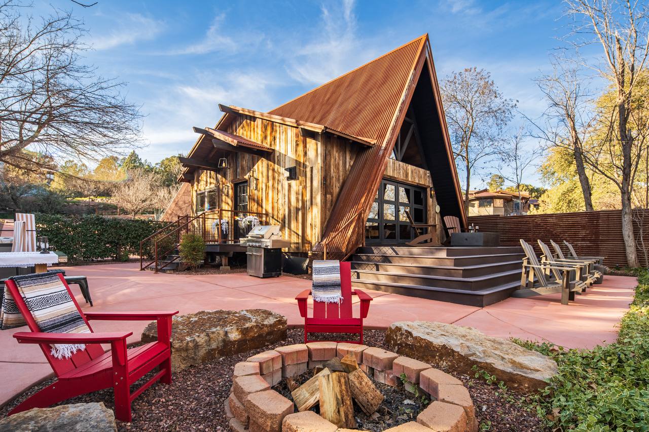 Full backyard with red chairs and stone fire pit