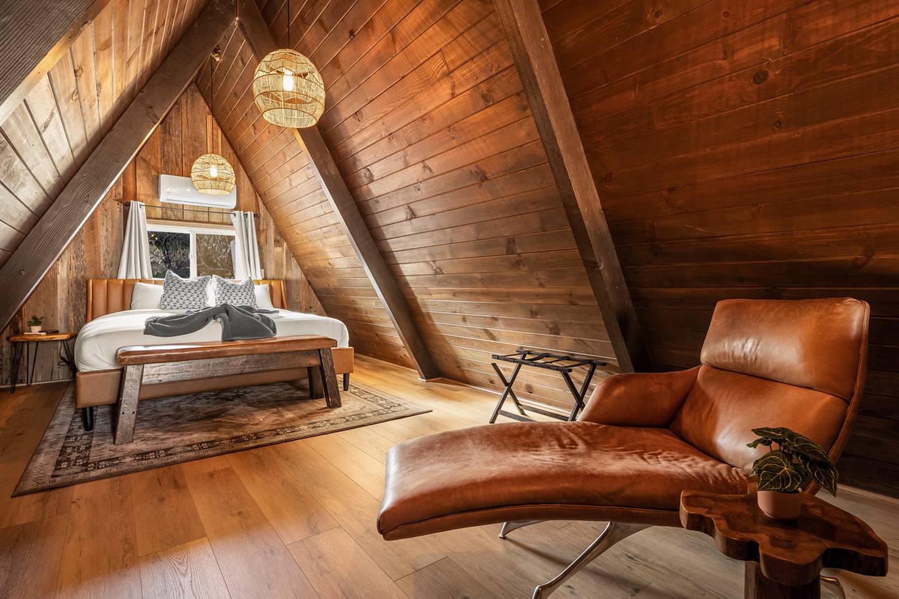 Loft bedroom with leather chaise lounge and A-frame wood ceiling